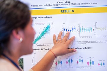 A researcher points to energy-balance closure plots on a conference poster.